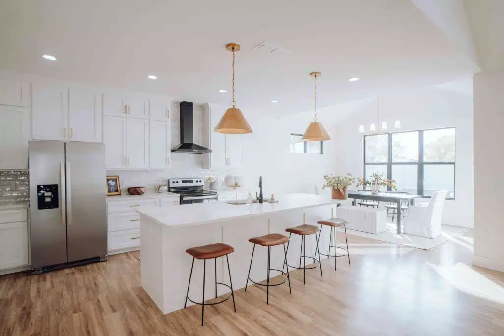 Modern kitchen interior design featuring a center island with stools, bright lighting, and a clean, stylish layout